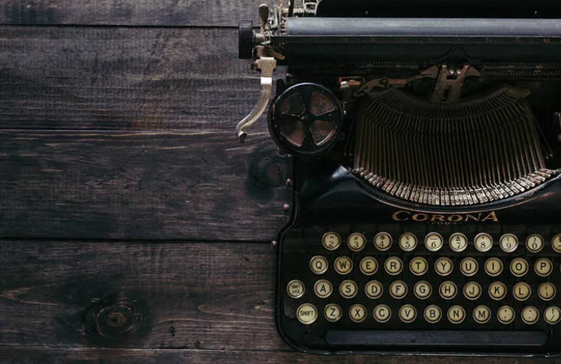 Máquina de escribir antigua sobre una mesa de madera oscura.
