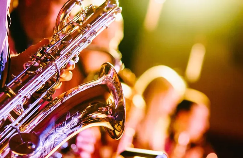 Persona tocando un saxofón en un escenario iluminado.