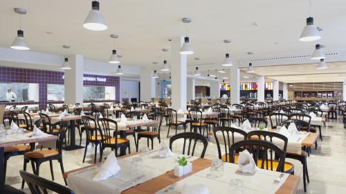 Restaurante amplio y bien iluminado con mesas preparadas, sillas negras y decoración moderna.