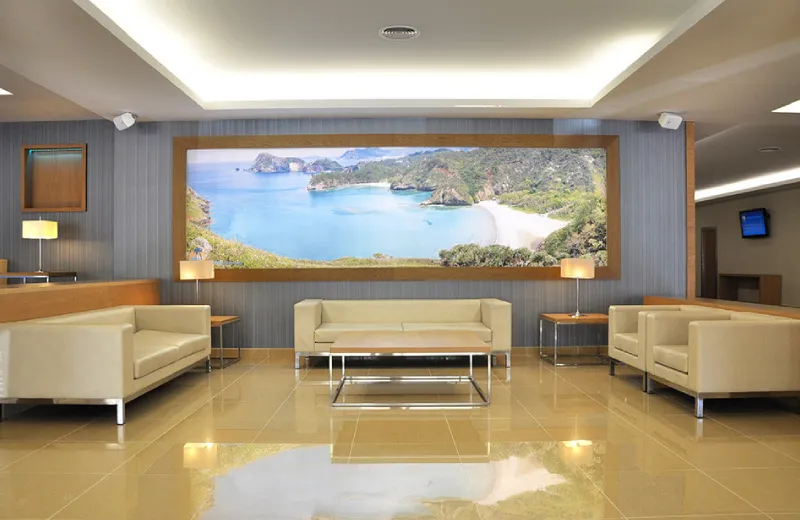 Sala de espera moderna con muebles beige y gran cuadro de paisaje costero en la pared.