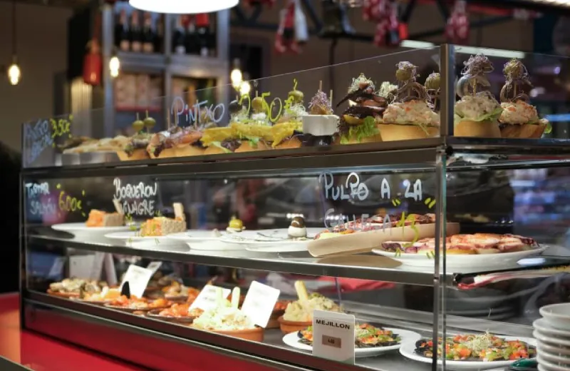 Vitrina de tapas en un bar, con variadas opciones de pintxos y raciones expuestas.