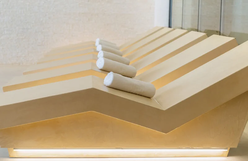 Sillas reclinables en fila, cada una con una toalla enrollada sobre el respaldo.