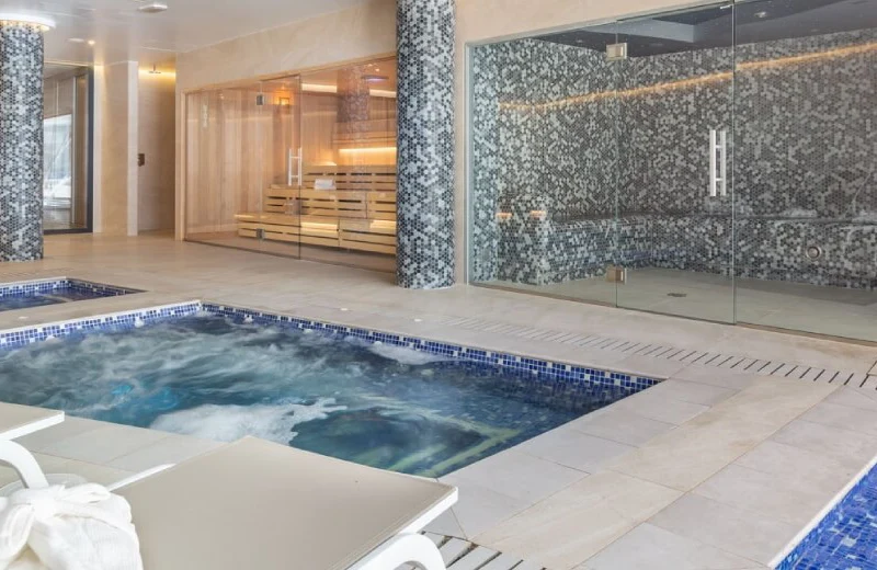 Spa con jacuzzi, sauna y vapor, decorado con azulejos azules y paredes de cristal.