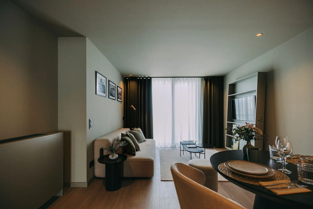 Modern living room with sofa, dining table, TV, and large window with curtains.