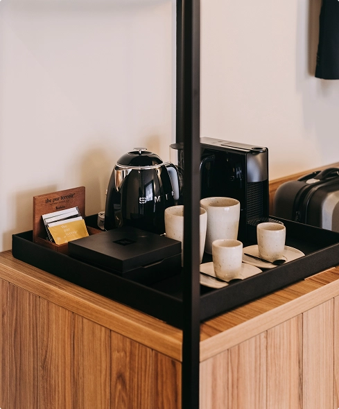 Tea and coffee station with kettle, cups, and toaster on a wood surface.