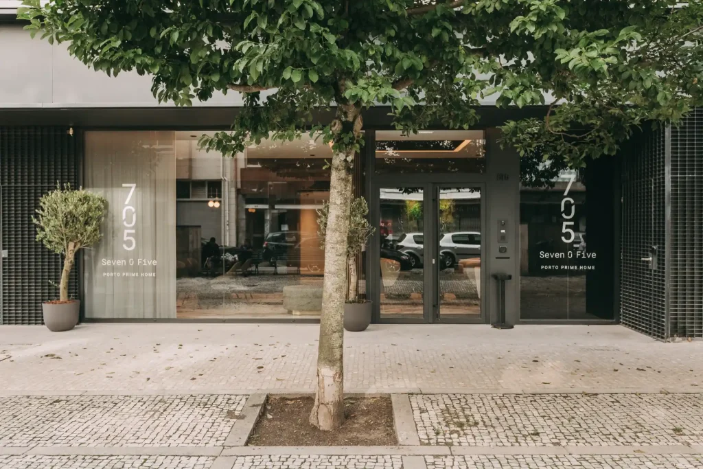 Facade of a modern building with a tree and glass doors.