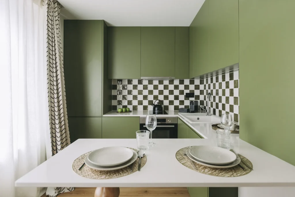 Green kitchen with checkerboard tiles, table set for two.