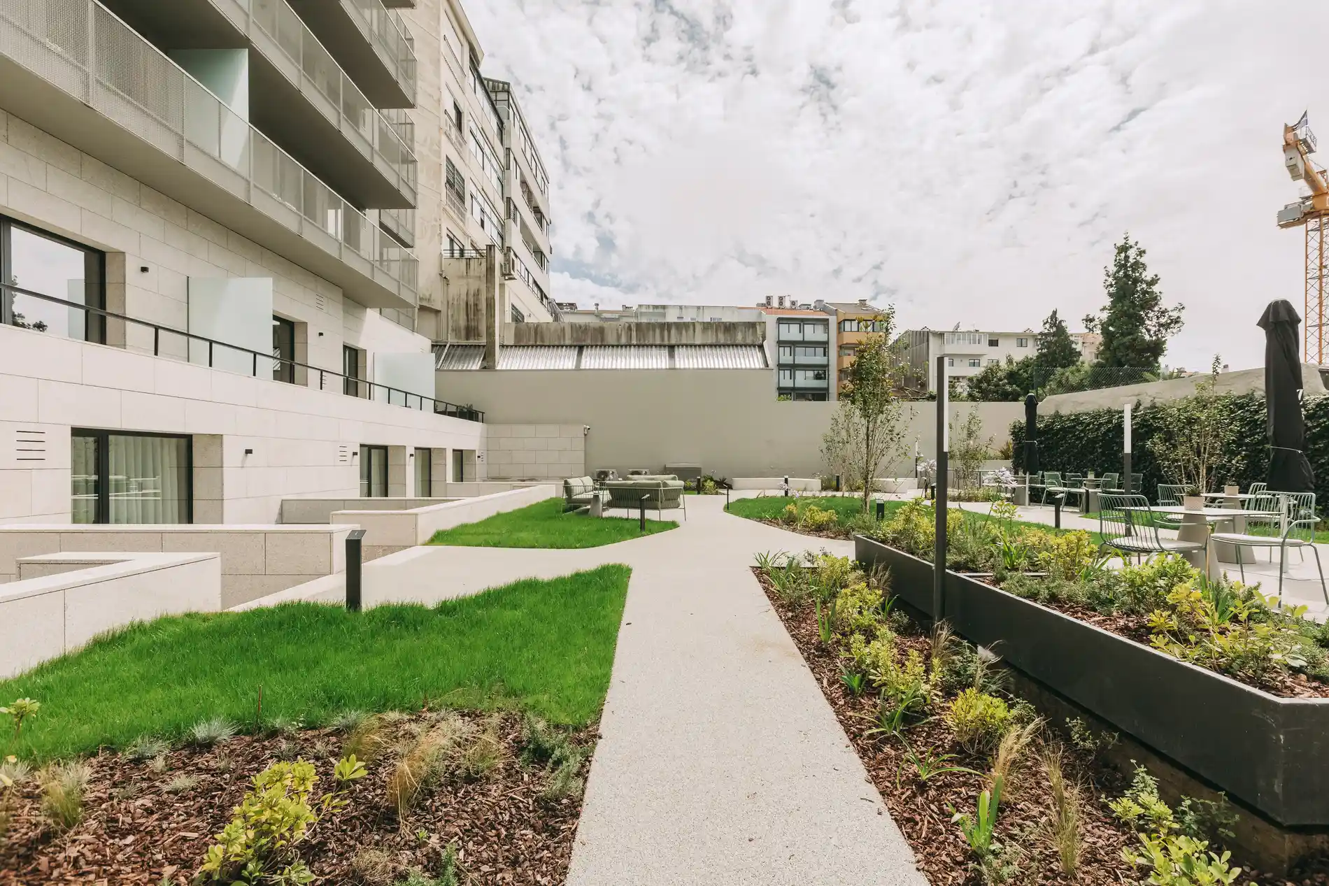 Modern apartment building courtyard with greenery and outdoor seating.