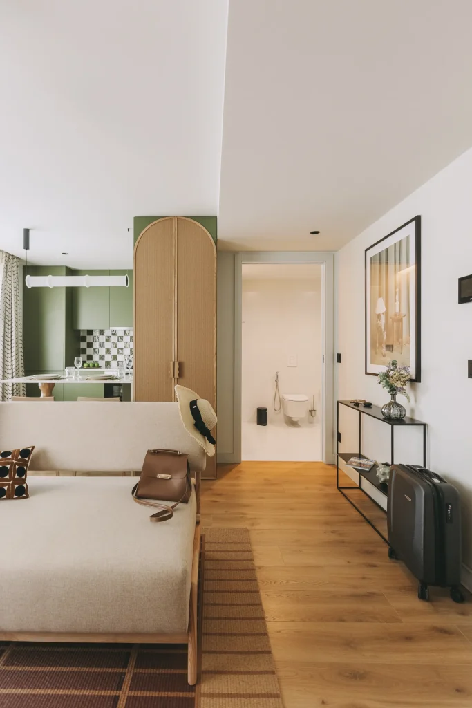 Modern living room with light decor, open kitchen, and visible hallway to a bathroom.