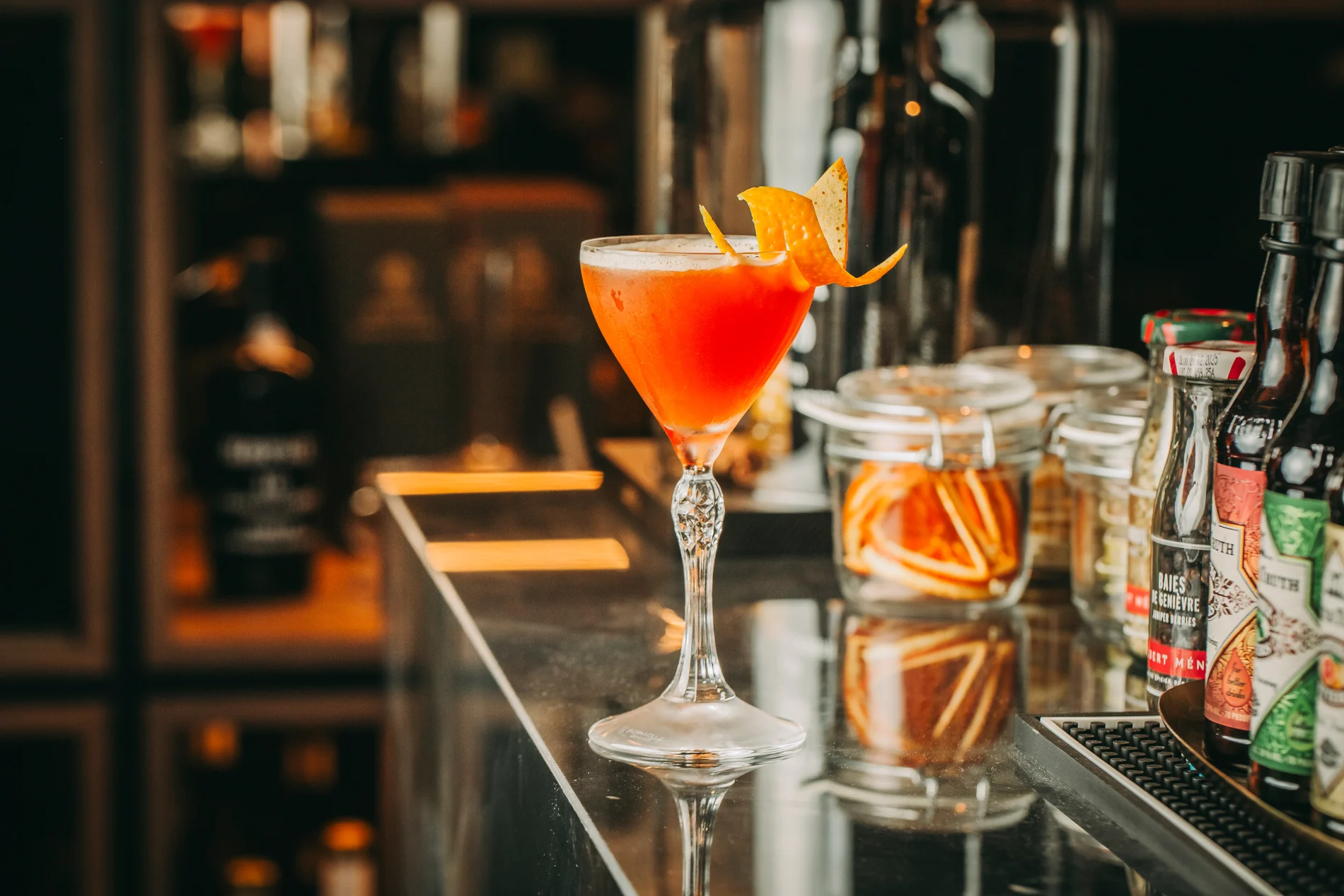 A vibrant cocktail with orange garnish on a bar counter.