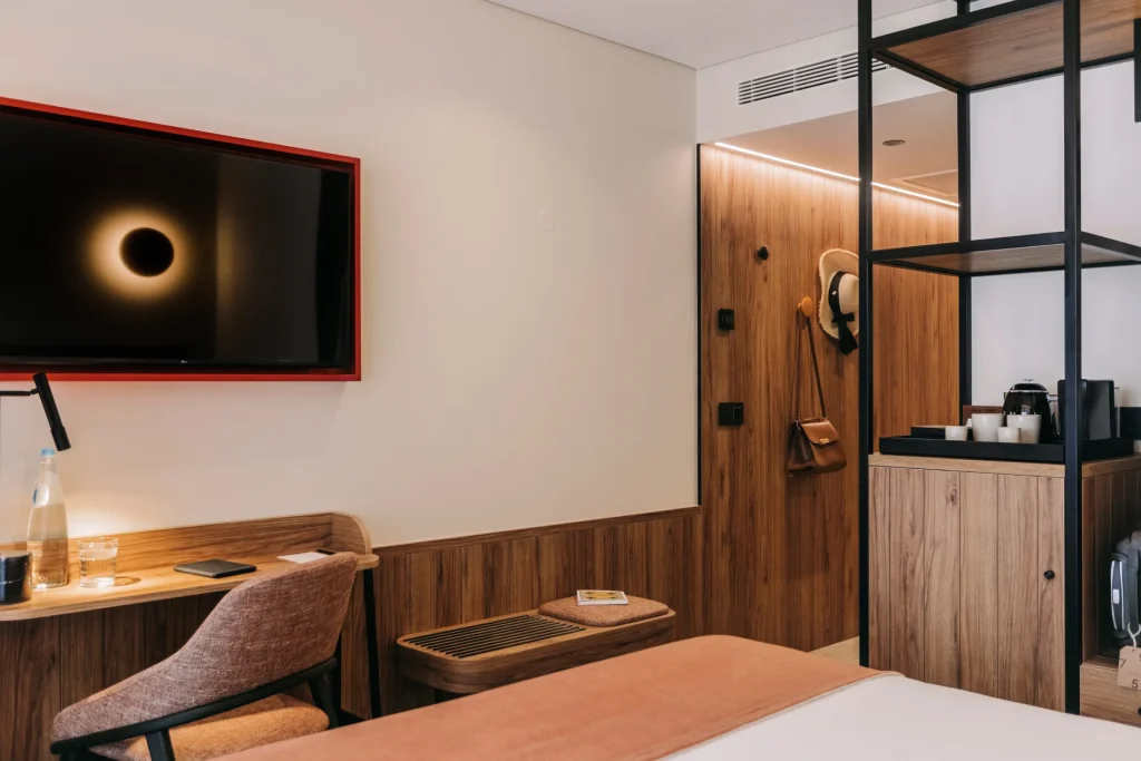 Cozy hotel room with a bed, TV, desk, and wooden decor.