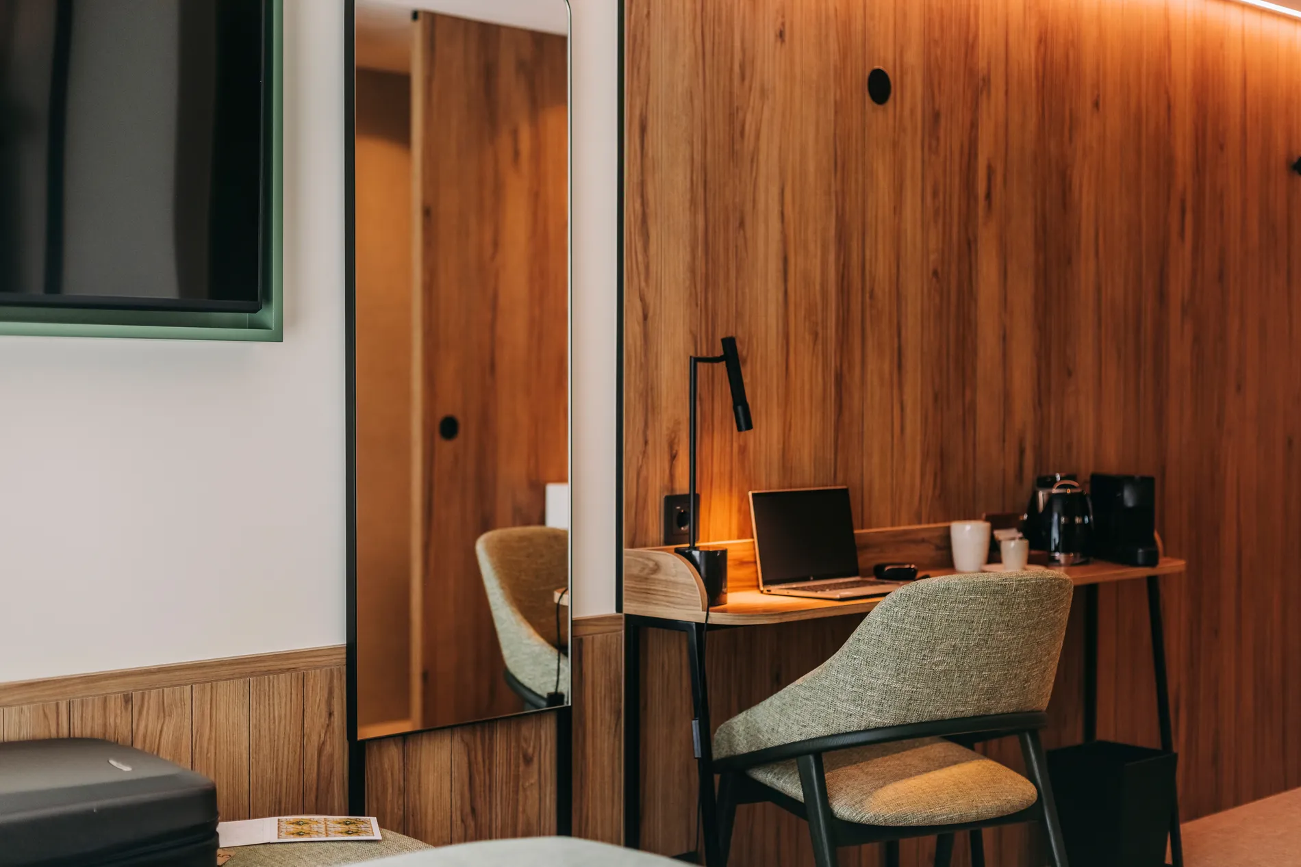 Cozy hotel room with a wooden desk, laptop, chair, and coffee maker.