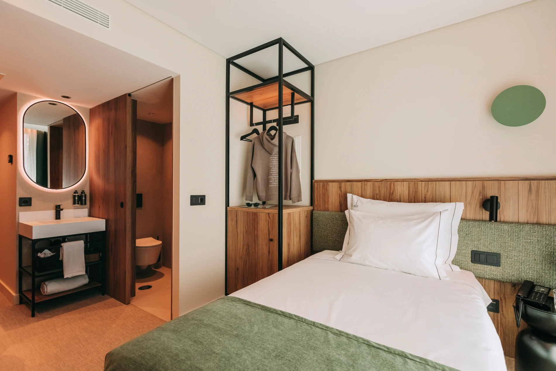 Cozy hotel room with a bed, closet, and a bathroom in the background.