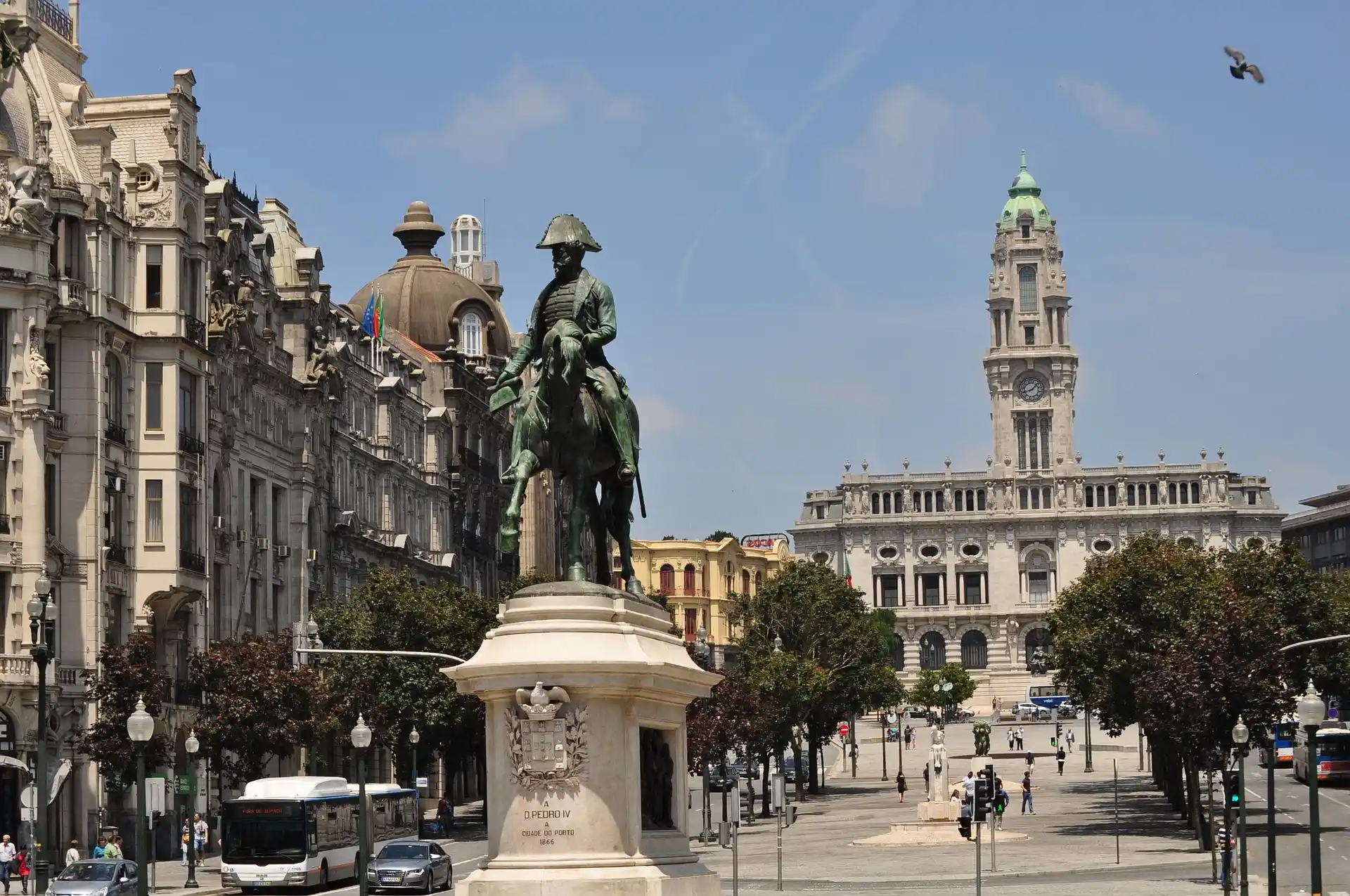 City square with an equestrian statue, historic buildings, and a clock tower in the background.