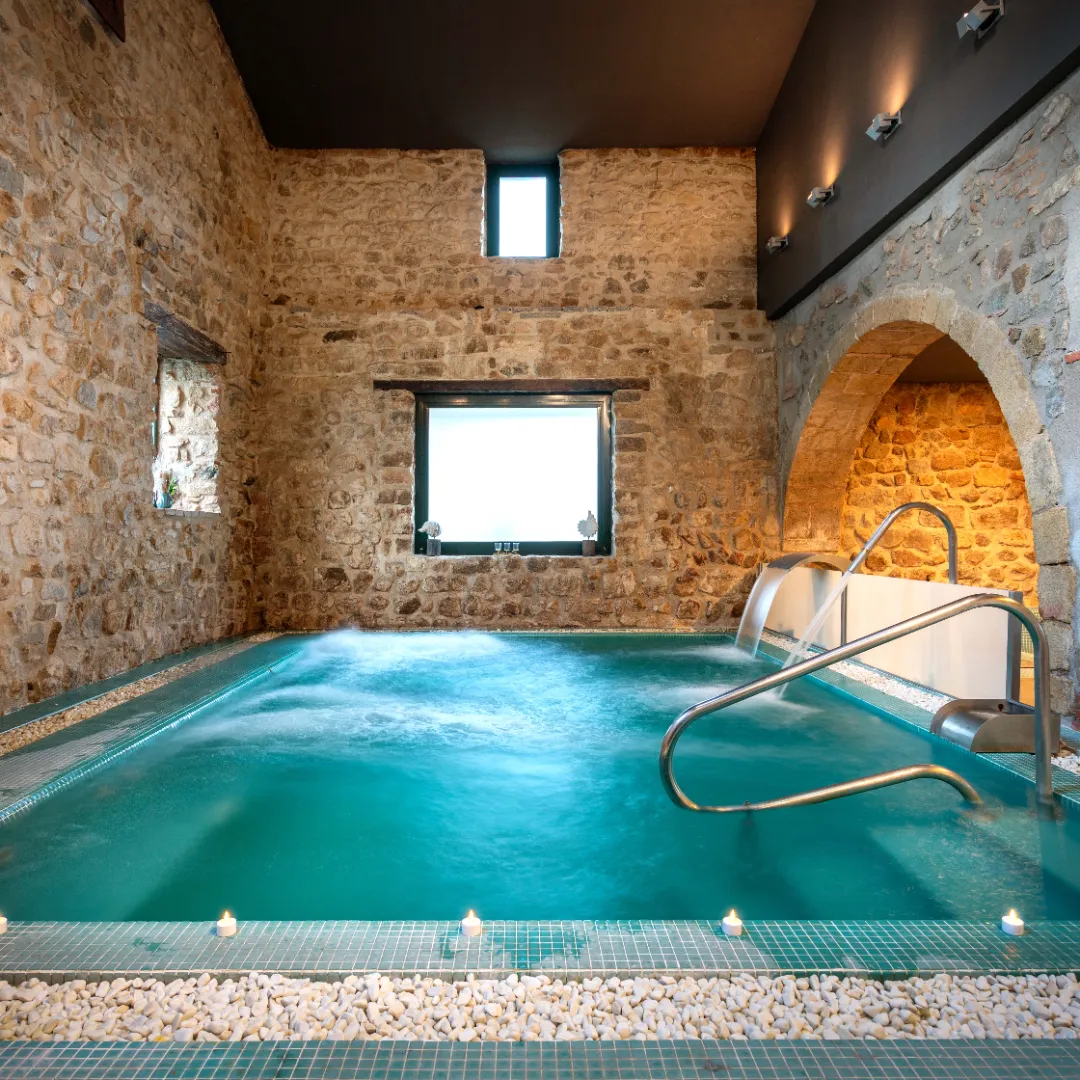 Un muro de piedra gris, con textura rugosa y musgo en algunas áreas, se eleva contra un fondo natural.