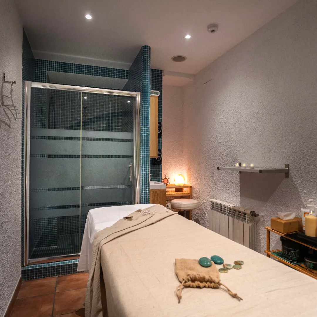 Sala de spa con una cama cómoda y una ducha moderna, decorada en tonos suaves y relajantes.