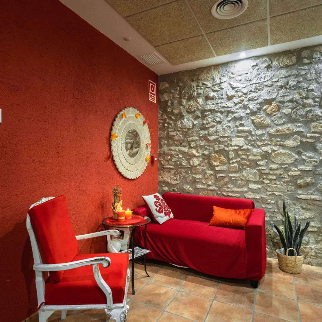 Sofá y silla rojos en una habitación con pared de piedra.