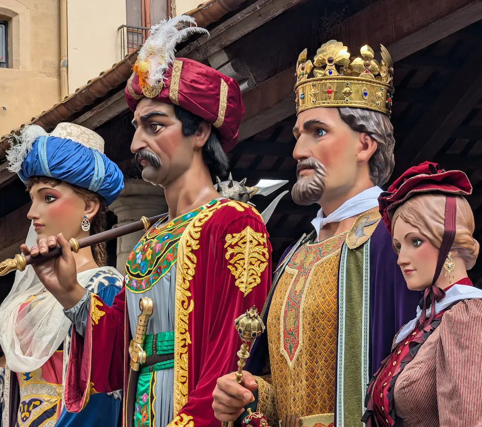 Cuatro figuras gigantes de carnaval con trajes medievales y renacentistas, en fila, adornadas con detalles coloridos.
