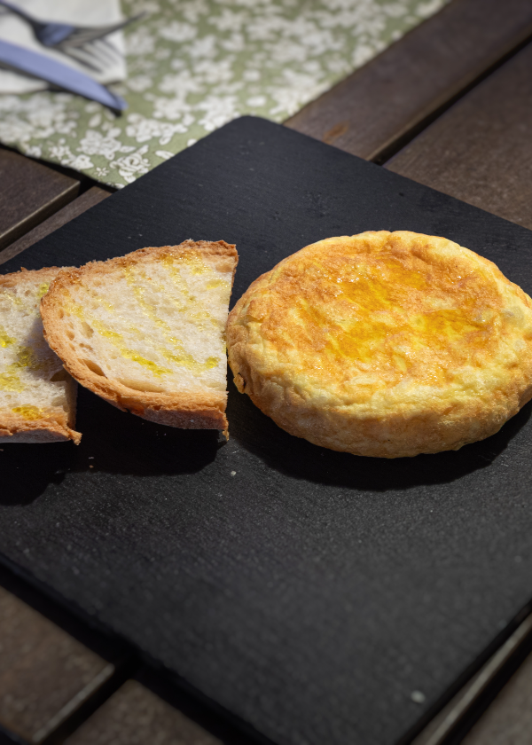 Un pequeño trozo de pan y un pedazo de queso sobre un plato negro.