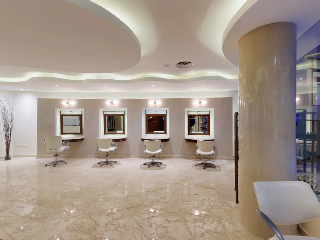 Modern salon interior with four styling stations, mirrors, and swivel chairs on a polished marble floor.