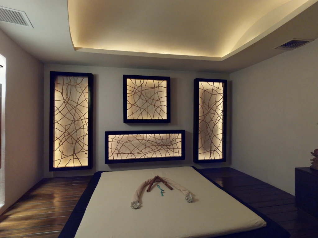 Modern minimalist room with illuminated geometric wall panels and a low bed with towels folded in swan shapes.