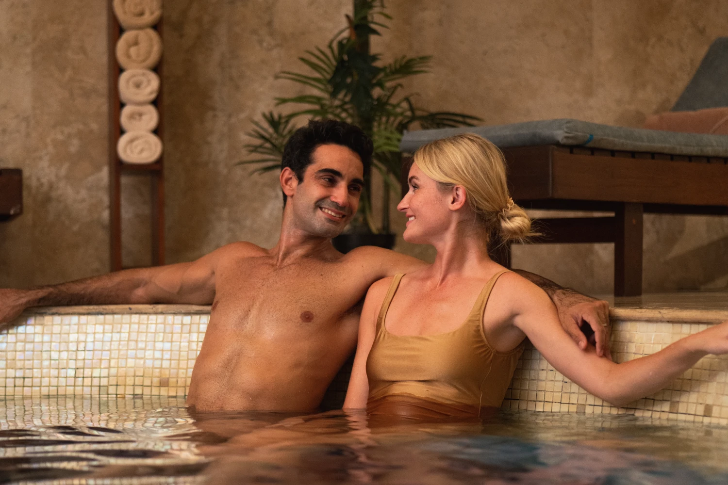 A man and woman smiling at each other while relaxing in a spa pool.