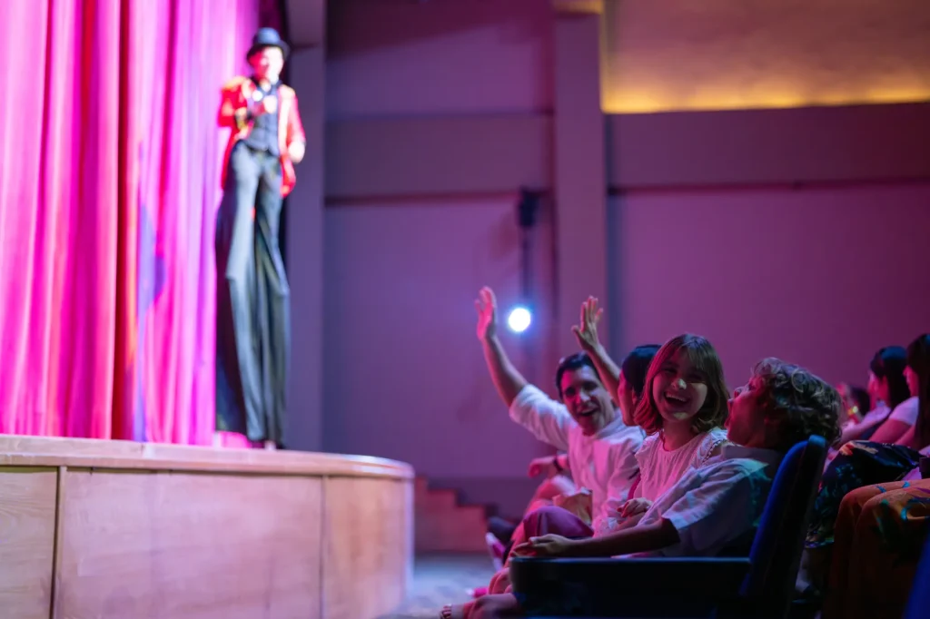 Performer on stilts entertains a joyful audience in a theater.