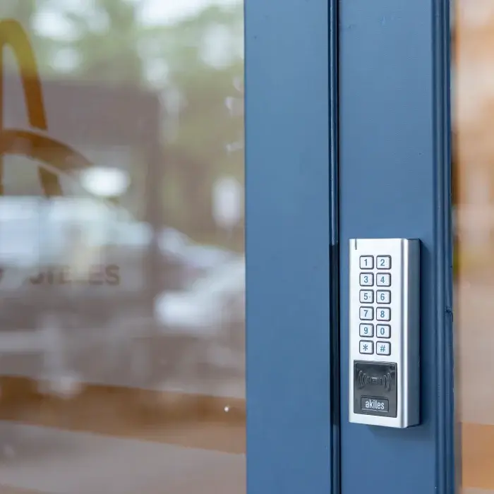 Teclado numérico en puerta azul para control de acceso.