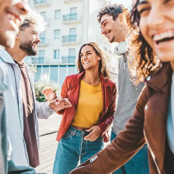 Un grupo de amigos riendo y conversando al aire libre durante el día.