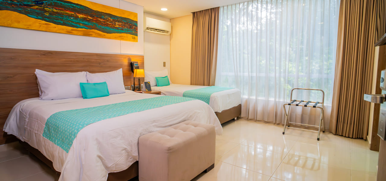 Habitación de hotel con dos camas, decoración moderna, ventanal con cortinas, y cuadro colorido en la pared.