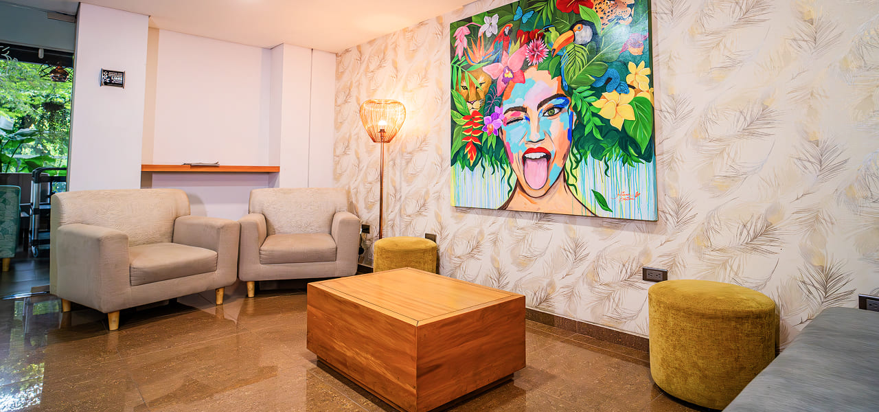 Sala con dos sillones grises, mesa de madera y cuadro colorido en la pared. Decoración moderna y acogedora.