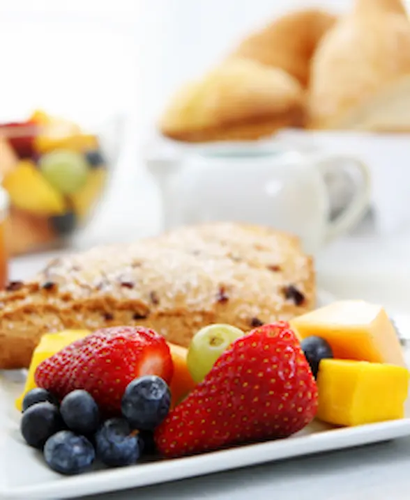 Assiette de fruits et fromage avec croissant en arrière-plan.
