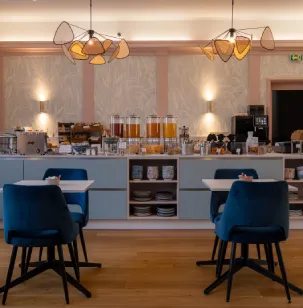 Salle de petit-déjeuner élégante avec chaises bleues, comptoir buffet et luminaires modernes.