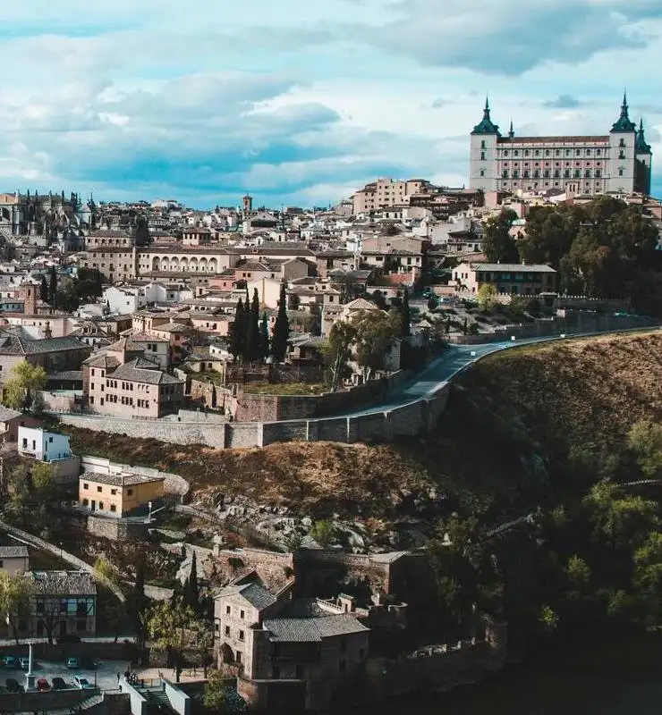Vista panorámica de una ciudad histórica con un gran edificio destacado bajo un cielo nublado.