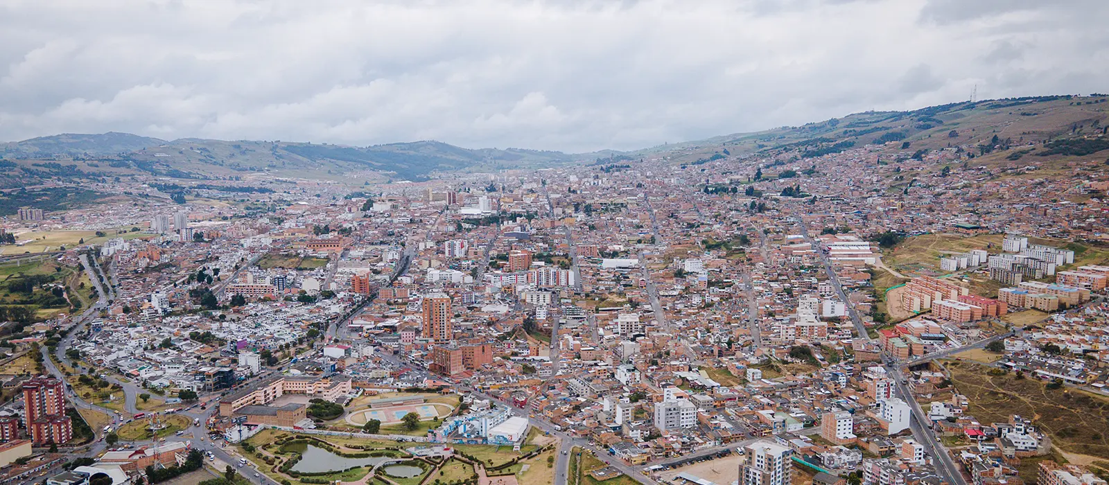 Vista aérea de la ciudad de Tunja con edificios y colinas en el horizonte bajo un cielo nublado.
