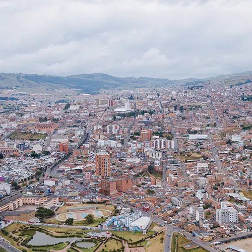 Vista aérea de la ciudad de Tunja con edificios, colinas y un cielo nublado.