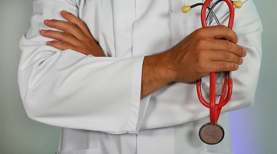 Doctor en bata blanca con estetoscopio rojo en la mano.