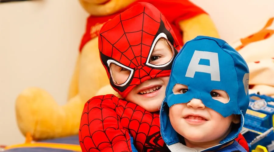 Niños disfrazados de superhéroes sonríen mientras juegan juntos.