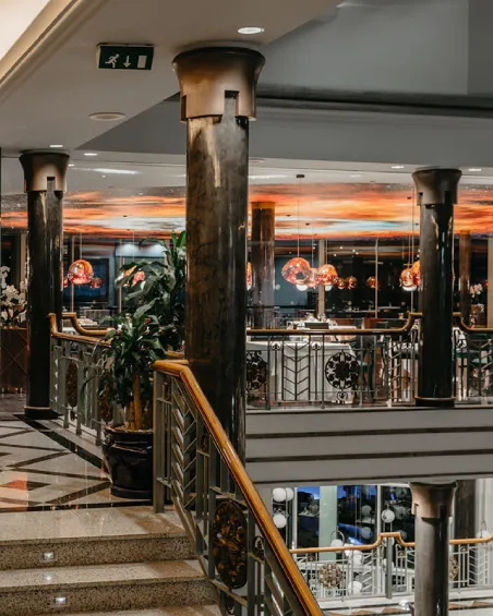 Galería elegante con columnas oscuras y luces colgantes en un interior sofisticado.