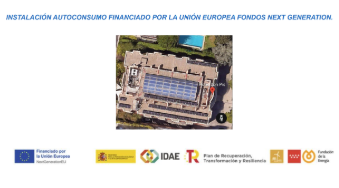 Vista aérea de un edificio con paneles solares y logotipos de la Unión Europea, IDAE, y otras instituciones abajo.
