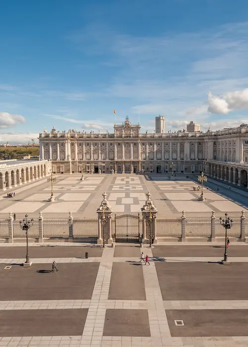 Patio del Palacio Real de Madrid bajo un cielo azul con algunas nubes.