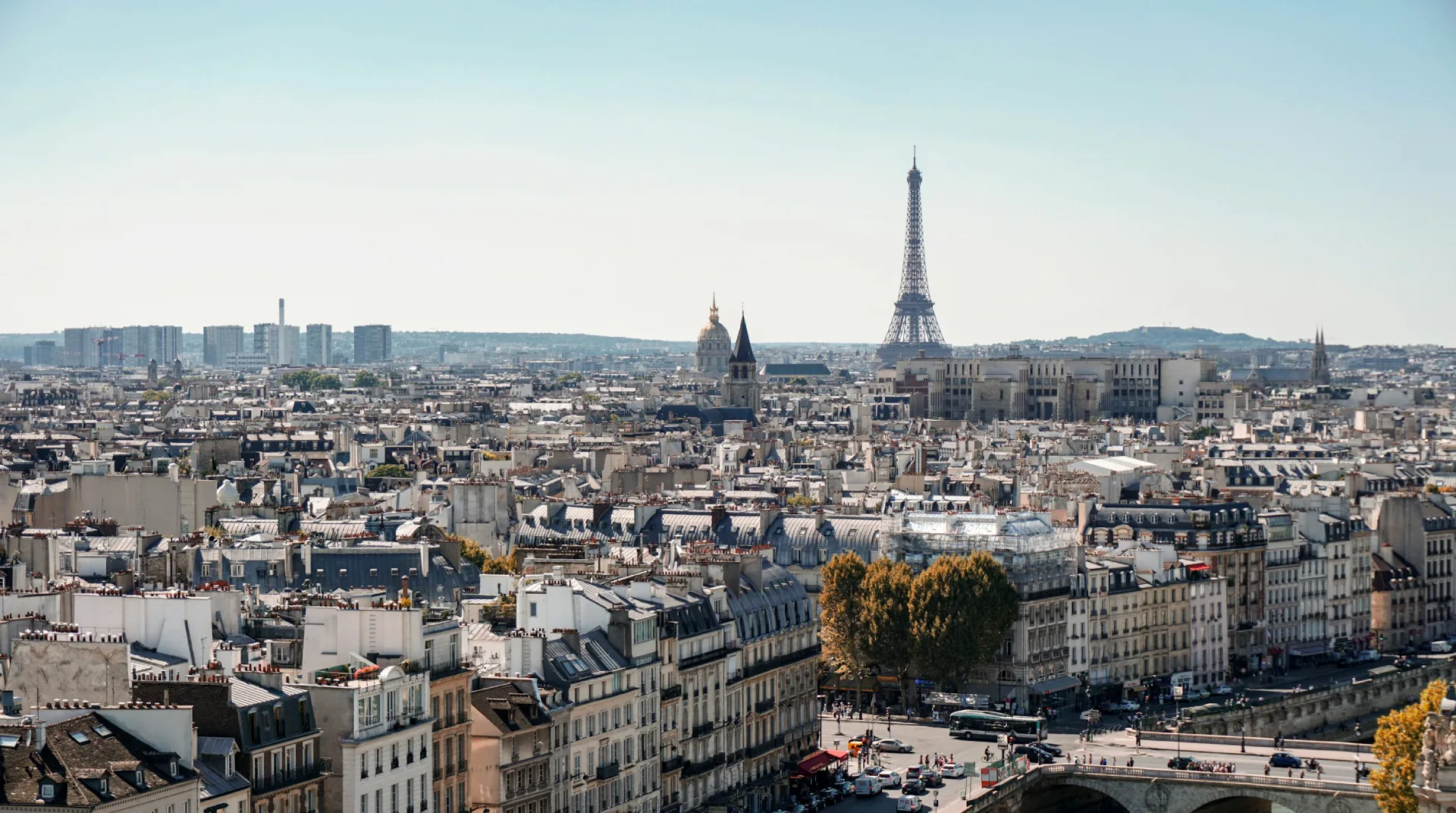 Vue panoramique de Paris avec la Tour Eiffel en arrière-plan sous un ciel dégagé.