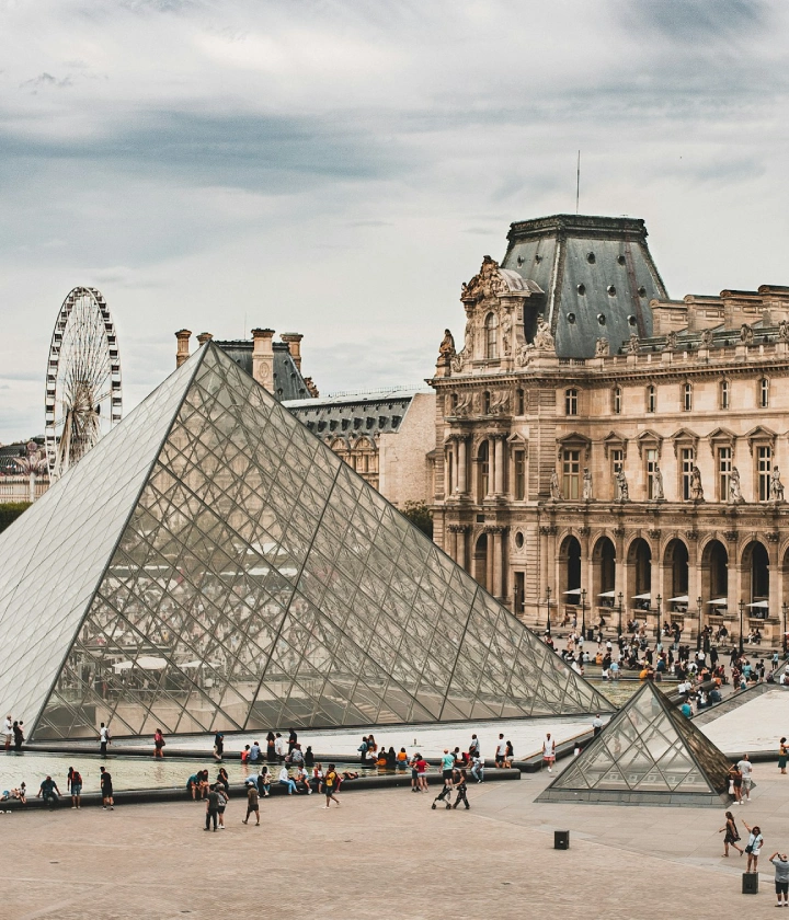 Pyramide en verre du Louvre à Paris avec une grande roue en arrière-plan.