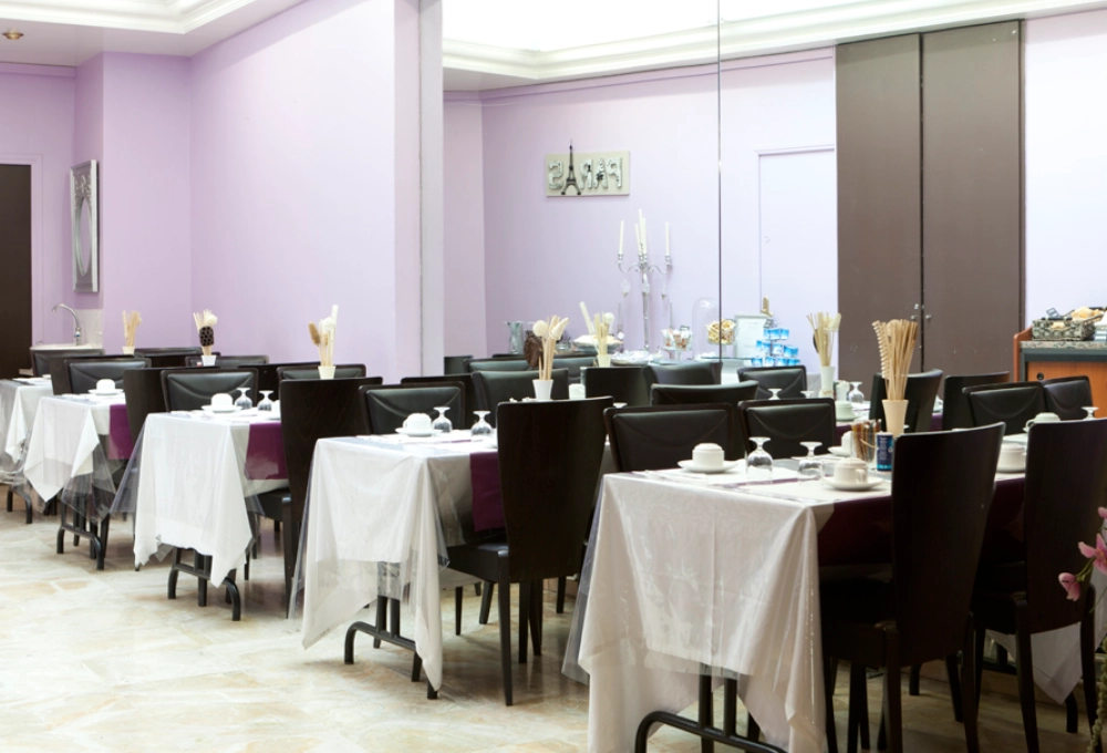 Salle à manger élégante avec chaises noires et nappes blanches dans un décor violet.