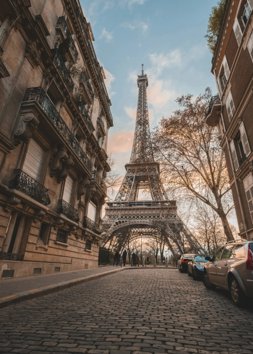 Rue pavée menant à la Tour Eiffel entre deux rangées de bâtiments parisiens.