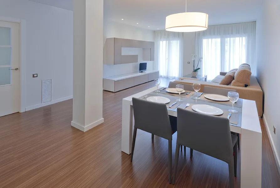 Sala moderna con comedor, sofá y televisor; iluminación suave y decor minimalista.