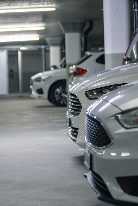 Autos blancos alineados en un estacionamiento subterráneo iluminado.