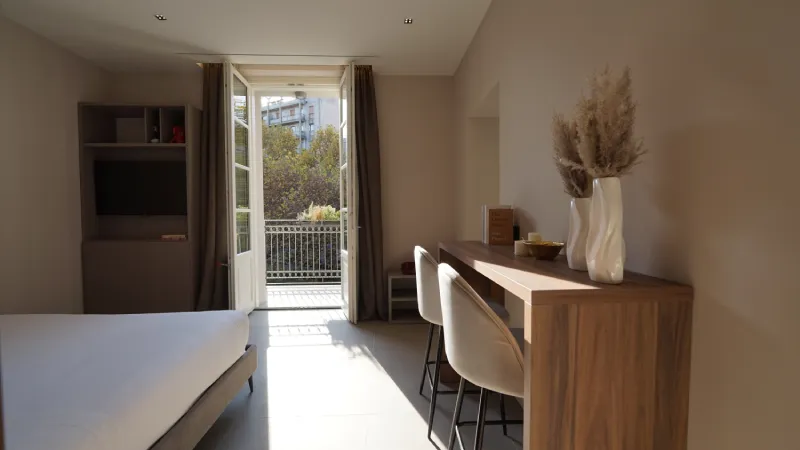 Habitación luminosa con mesa, sillas y puerta al balcón.