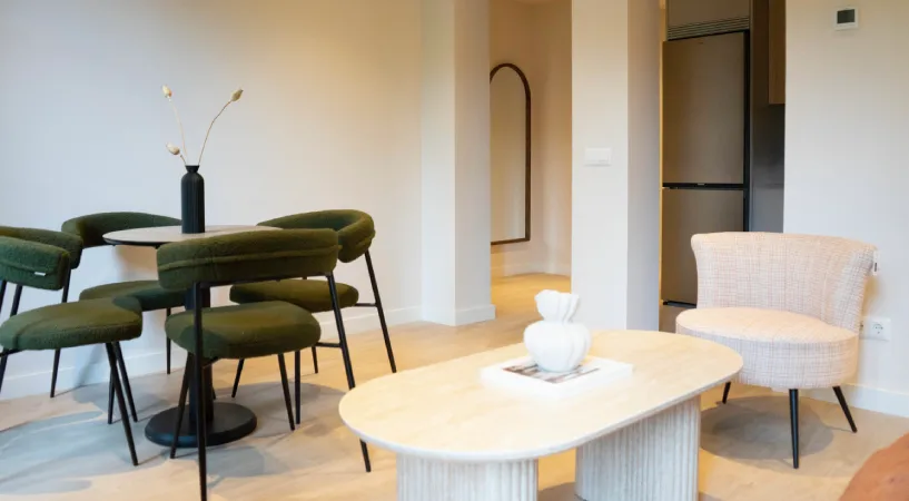 Sala de estar moderna con mesa beige y sillas verdes y blancas.
