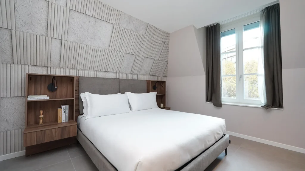 Habitaci&oacute;n moderna con cama grande y ventana al lado derecho.